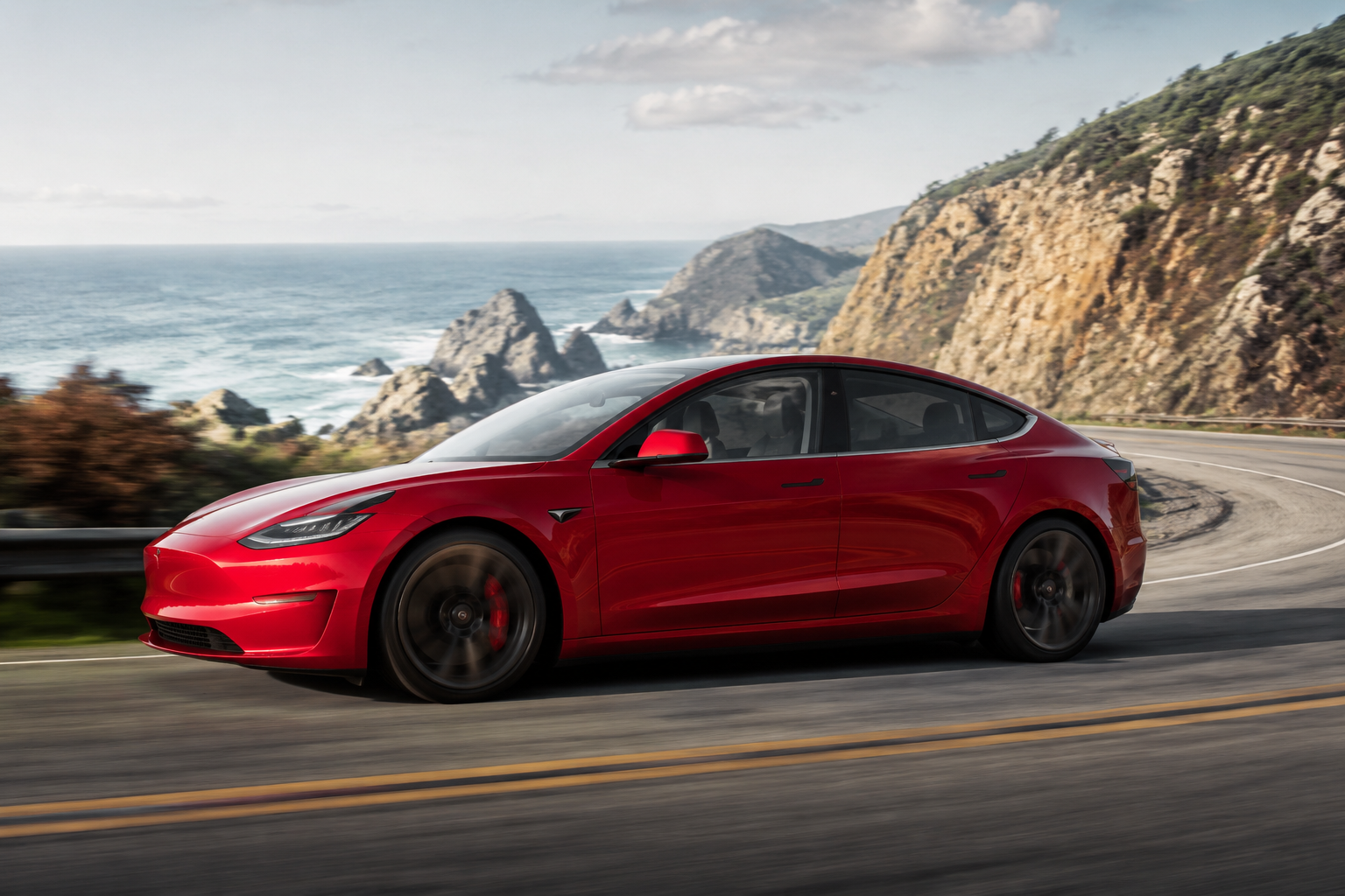 Red electric sport sedan on a winding coastal road